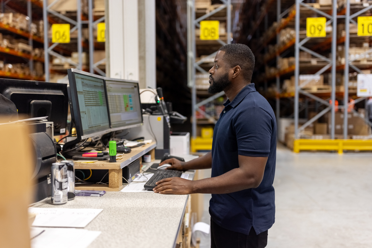 Man working on computer in large factory warehouse