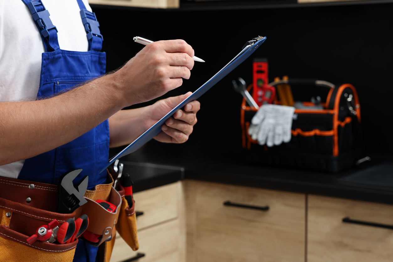 Professional plumber with clipboard and tool belt indoors, closeup. Space for text Managing Plumbing Projects