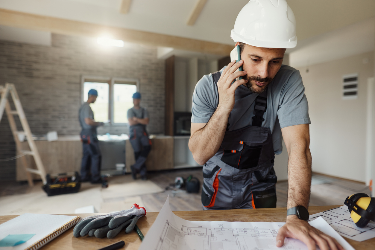 Manual worker talking on cell phone during home renovation process. Plumbing Emergency